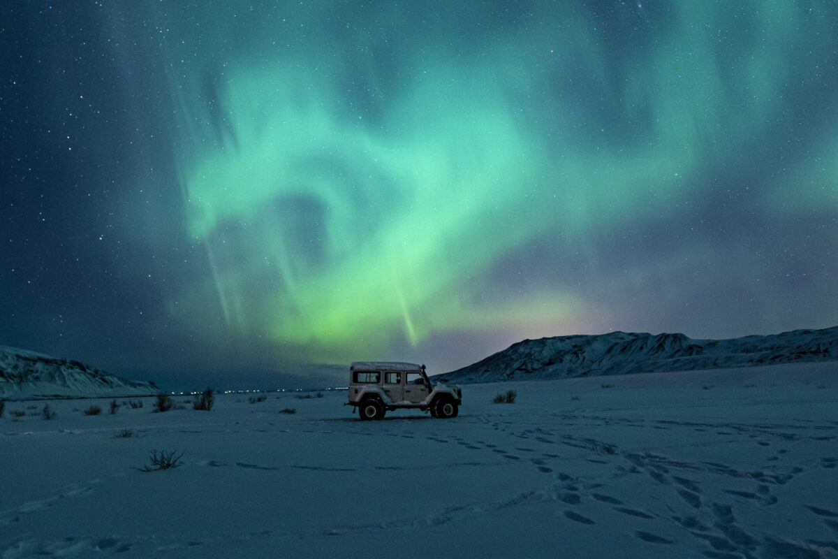 Black suv snow covered field green aurora lights
